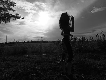 Woman standing on field against sky during sunset