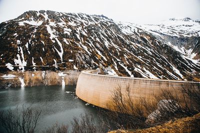 Scenic view of snow covered mountain with dam against sky