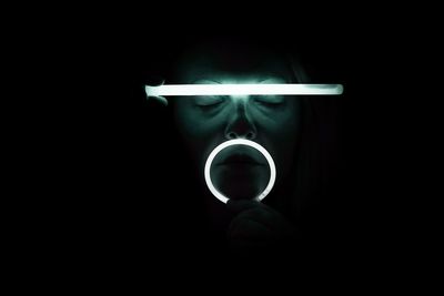 Close-up portrait of man holding cigarette against black background