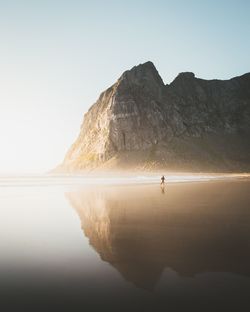 Person running at beach against rock formation