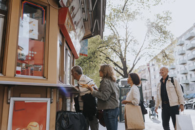 Male and female senior friends buying desert from ice cream shop at street