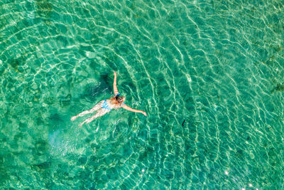 Aerial view of a girl floating in the turquoise sea on the cres island, adriatic sea, croatia