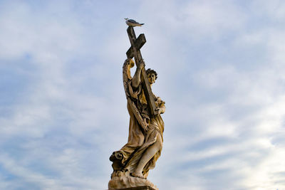 Low angle view of angel statue against cloudy sky