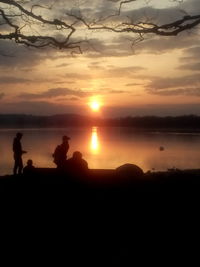 Silhouette people on beach against sky during sunset