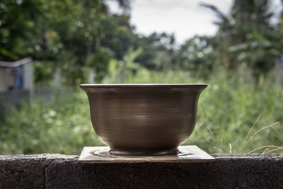 Close-up of bowl on table against trees