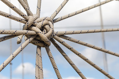 Close-up of rope tied on metallic structure against sky