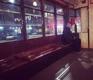 Man sitting by window at illuminated railroad station