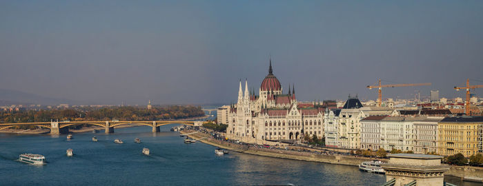 Bridge over river in city against sky