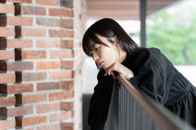 Young woman looking away against wall