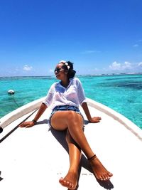 Full length of woman sitting on beach against sky