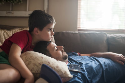 Father and son resting on couch in living room at home