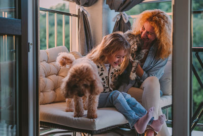 Happy child with smile plays on summer at home with mom, dog at sunset. cat, dog, pets family member