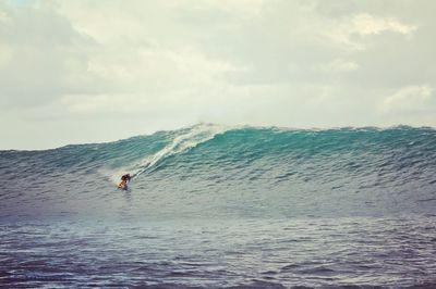 Man surfing in sea against sky