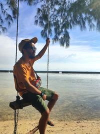 Man sitting at beach against sky