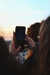 Cropped image of woman photographing against sky