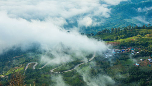 High angle view of winding road on mountain seen through clouds