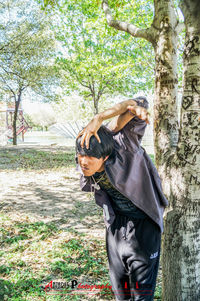 Woman standing on tree trunk