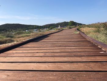 Surface level of wooden boardwalk against sky