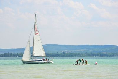 People in boat sailing on sea against sky