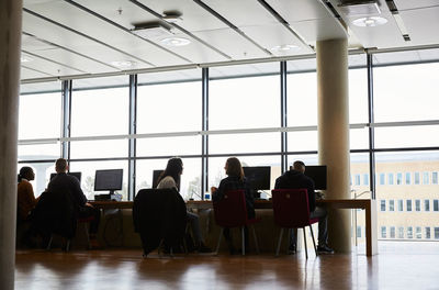 Male and female students talking while sitting in computer lab at university