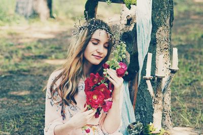 Portrait of a young woman by tree trunk