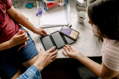 High angle view of family with solar panel and smart phone at table