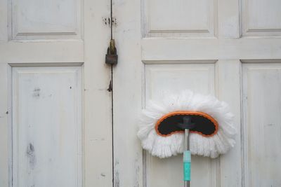 A white mop placed standing on the white vinatge door.