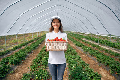 Portrait of smiling young woman standing in greenhouse