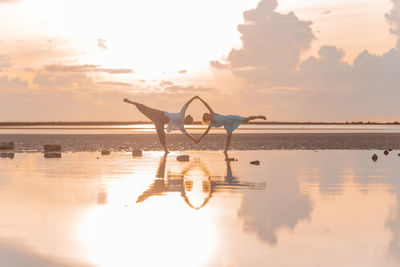 
real people stand in yoga assanas on the seashore at dawn