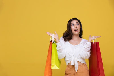 Young woman smiling against yellow background