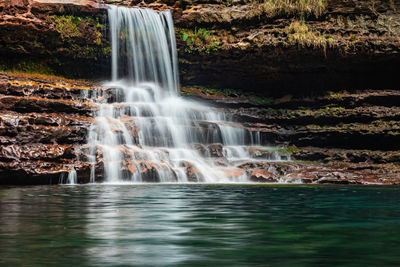 Waterfall streams falling from mountain with blurred water surface at morning from low angle