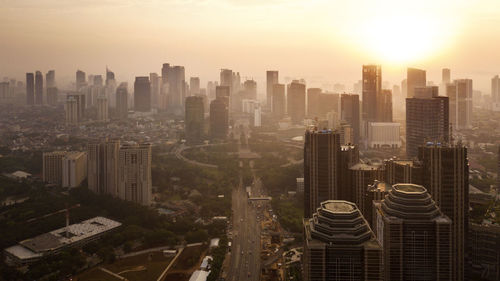Aerial view of buildings in city against sky during sunset