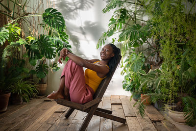 Portrait of woman sitting on chair against plants