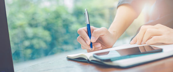Woman hand writing on a notepad with a pen in the office.web banner.