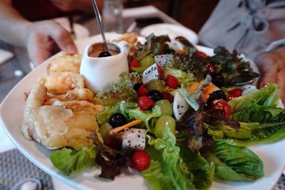 Close-up of hand holding salad served in plate