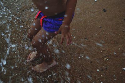 Low section of man standing on wet beach