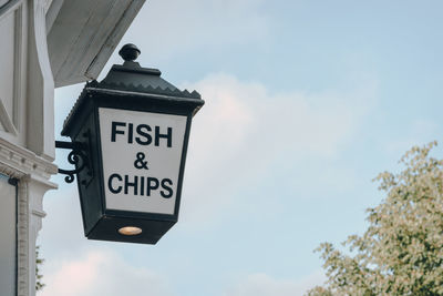 Low angle view of fish and chip sign outside a restaurant in london, uk, against the sky.