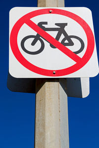 Low angle view of road sign against blue sky