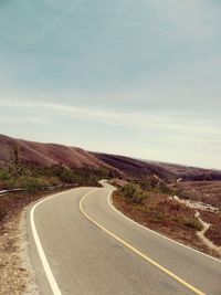 Empty road along landscape against sky