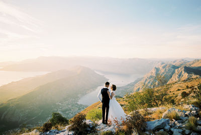 Rear view of man standing on mountain against sky