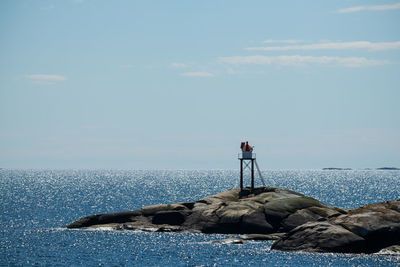 Man on rock by sea against sky