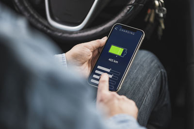 Woman operating electric car through mobile app on smart phone