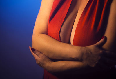 Midsection of seductive woman against blue background