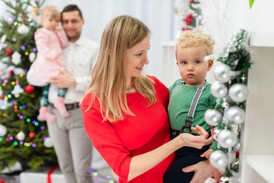 Portrait of smiling young woman standing against christmas tree