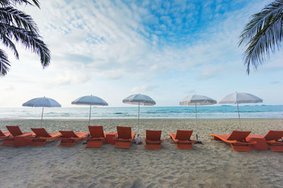 Chairs on beach by sea against sky