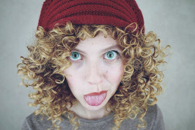 Portrait of young woman sticking out tongue against gray background