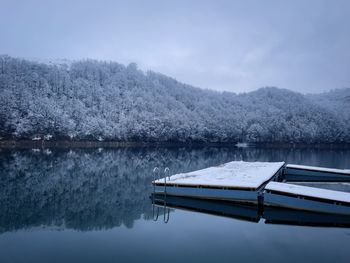 Wooden pontoon on the lake in winter and forest covered in snow on the other side