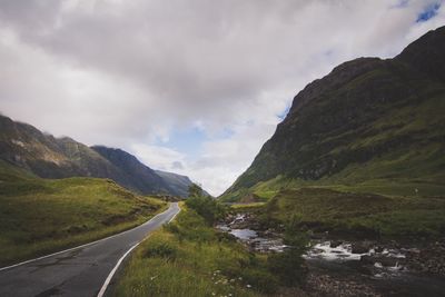 Scenic view of road by mountains against sky