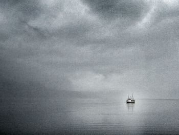 Boats in sea against cloudy sky