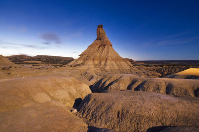 Scenic view of arid landscape against blue sky